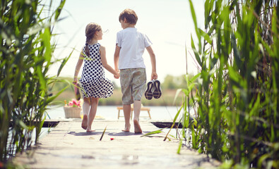 Boy and girl near pond.Kids during  goes on the pond.