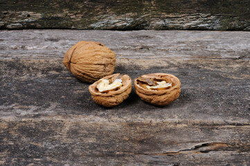 Two halves of walnut on a wooden surface. Front view.