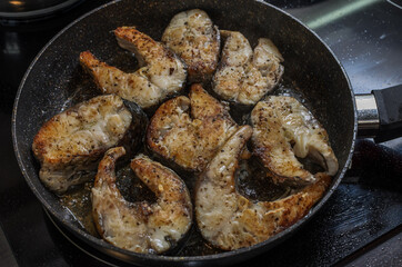 Fish steaks fried in a pan on an induction stove	
