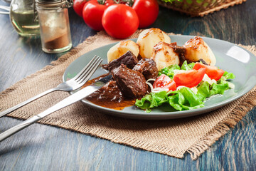 Pork meat stew served with potatoes and vegetable salad