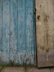 Old dirty white door and peeling blue wooden wall.
