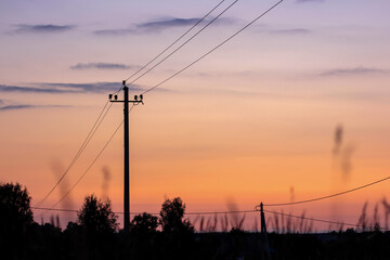 Silhouette of electric pole on meadow at sunset. Electricity, nature, sunset concept.