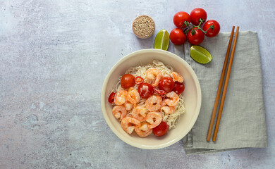 Keto dietary noodles shirataki konjak with shrimps and tomatoes in a bowl with chopsticks. Gluten-free and weight-loss food. Copy space for recipe or text.