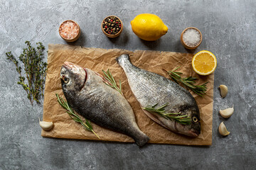 Preparing to cook or grill fresh raw dorado fish with ingredients on craft paper.