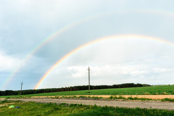 Summer rainbow landscape. Houses and field in the countryside in the background.