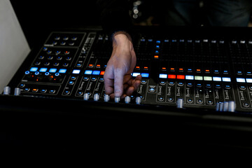 mixing console, a lot of faders and buttons. sound engineer hand