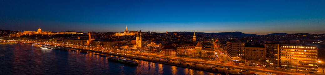 Aerial drone shot of St. Anne Parish church by Danube river at Budapest dusk city lights on