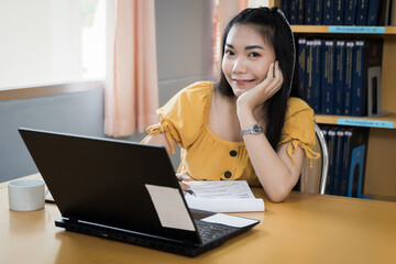 A teenager student studies online via laptop. University student girl watches online classes and writing a syllabus in a notebook. Concept of distance study, online learning, webinars. Stock photo.