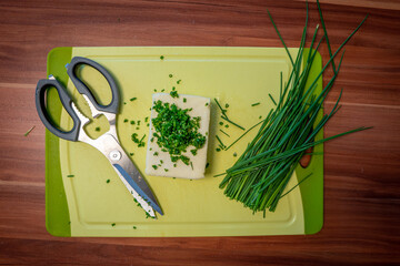 on cutting board lie butter, chives and scissors to prepare herb butter