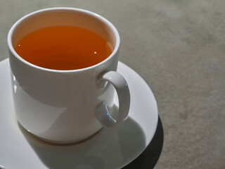 White ceramic cup with green tea on a dark table.