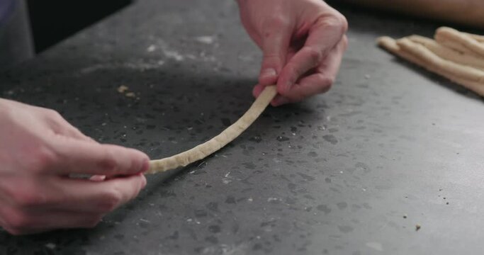 Slow motion man making grissini on concretre countertop