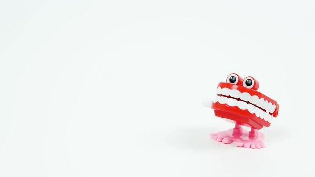 Chattering teeth toy walks into focus on the right side, white background