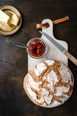 Ein Laib Brot, Konfitüre und Butter auf einem goldenen Teller, Draufsicht, rustikaler Hintergrund, Frühstück, Österreich
