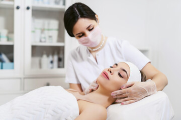 Beautician performs facial massage for a young woman in a beauty clinic or spa salon. Cosmetology treatment. Perfect skin concept. Eternal youth.