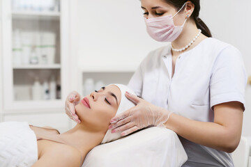 Beautician performs facial massage for a young woman in a beauty clinic or spa salon. Cosmetology...