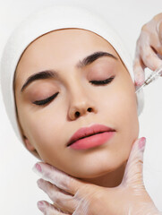 Cosmetology treatment in a clinic or beauty salon. Close-up face injection for a young woman. Beautician at work. The concept of perfect smooth clean skin and eternal youth