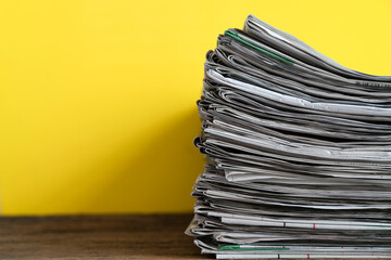 close up newspapers folded and stacked on yellow background on the table