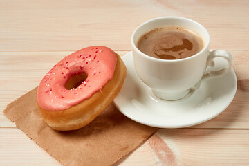 Cup of coffee, sweet donut with pink icing
