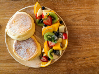 Pancakes with many fresh fruits on a wooden table