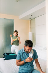 Young couple wearing medical masks and packing in hotel room