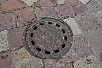 A manhole in the middle of the stone pavement
