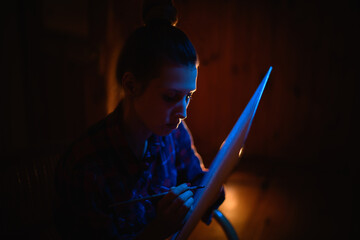 young female artist in dark room with brush in her hand