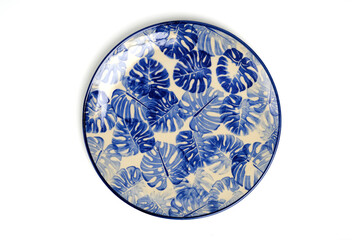 Ceramic plate with blue Monstera Plant Leaves pattern isolate on white background.