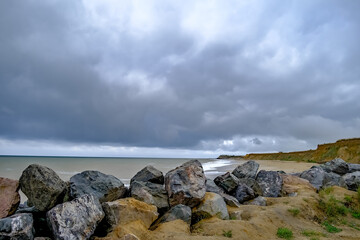 Fototapeta na wymiar 3 The rocky barrier protecting the sandy cliffs on a stormy day on Happisburgh beach, North Norfolk coast