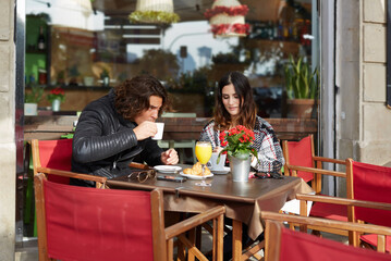 Two student friends drinking cafe after university classes in a restaurant terrace outdoors at cold...