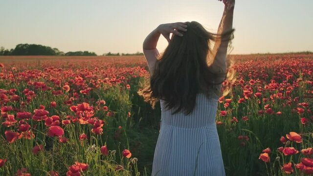 Unrecognizable female rumpling hair in blooming meadow