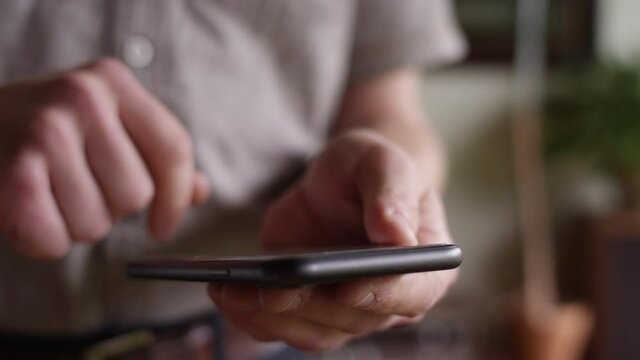 Man swipes and makes selections with his smartphone with shallow focus