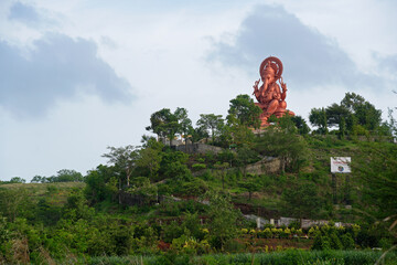 Lord Ganesha statue on a hill with green trees & blue sky. A public place shot at Somatane phata in Pune on 20 june 2020