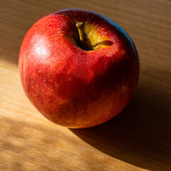 Red apple lies on an oak board.