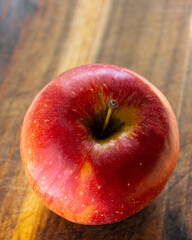 Red apple lies on an oak board.
