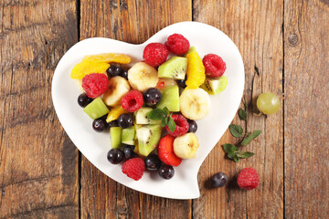 Fototapeta na wymiar fresh mixed fruit salad in heart shape plate