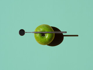 green apple and angled mirror on turquoise background. horizontal. dental concept