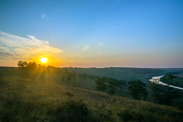   Sunrise over the hill, field and river. Bright sky and dark earth. Dawn Dawn. The sun above the horizon, horizon.
