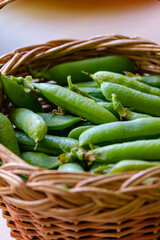 Green pea pods in a straw basket