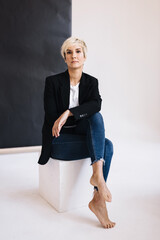 Blonde girl in a pantsuit in the studio on a white background