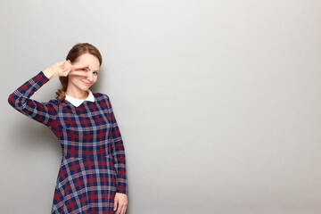 Portrait of cheerful girl showing victory or peace gesture near eye