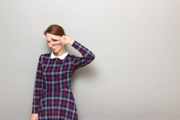 Portrait of cheerful girl showing victory or peace gesture near eye