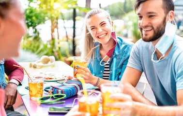 Friends drinking at cocktail bar with opened face masks - New normal friendship concept with people having fun together toasting drinks at fashion dinner - Bright vivid filter with focus on woman