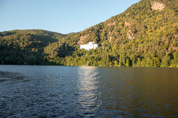 Fototapeta na wymiar skyline of Monticchio lake in the sunset. It is an amazing lake with church near them. The lake is in a wonderful forest with a lot of trees on the hills with a white church