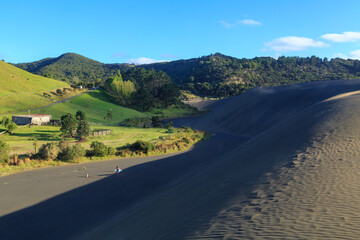 A giant inland sand dune at Bethells Beach, New Zealand, casting a shadow on the landscape