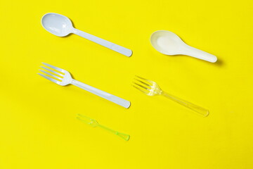 white plastic spoon and fork arranging on yellow foam board background