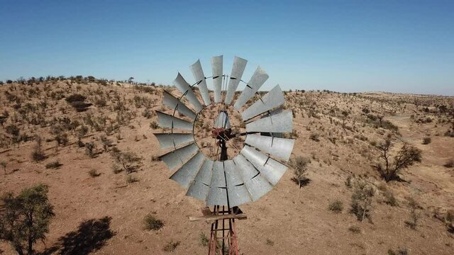 4K aerial drone video of Africa savanna hills, plains and farm wind water pumps on pillars in dry riverbed near Neuheusis west of Windhoek in central highland Khomas Hochland, Namibia, southern Africa