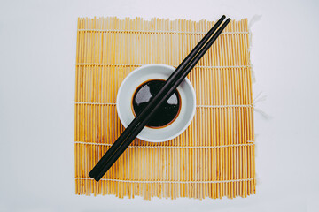 Stock photo Japanese soy sauce with traditional chopsticks and sushi mat isolated white background