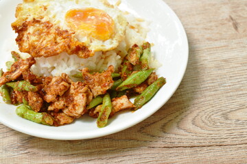 spicy fried pork with slice yard long bean in curry on rice topping egg