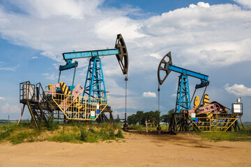 Fototapeta na wymiar The rigs pump working on oil field at summer