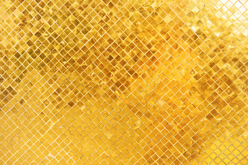 Closeup view of wall surface with many gold shiny mosaic squares. Can be used as metallic gold background